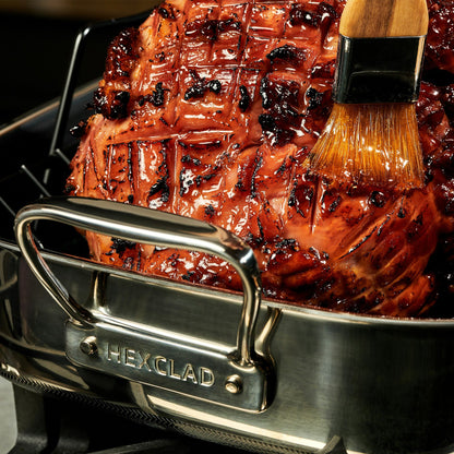 A large piece of meat inside the HexClad Hybrid Roasting Pan being braised with a brush.